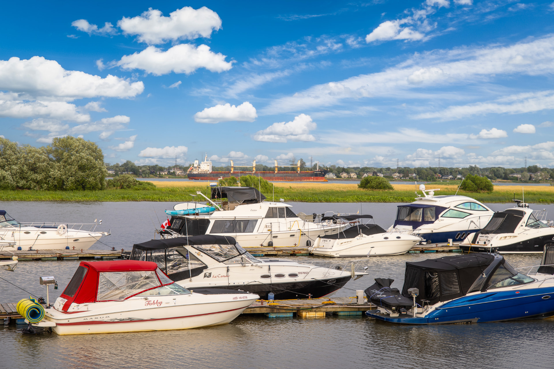 Bateaux amarrés à une marina, face à la Villa Océane, avec le fleuve Saint-Laurent en arrière-plan